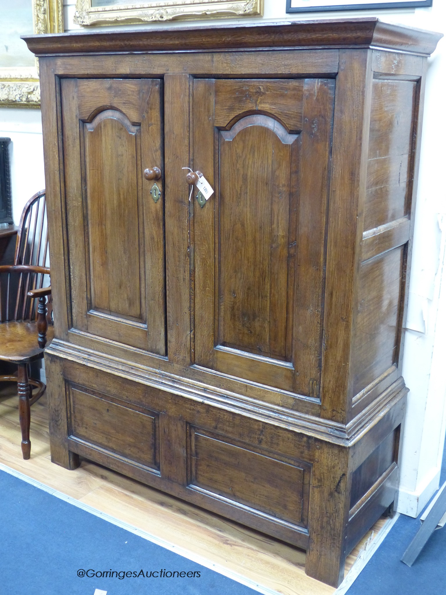 An early 18th century oak cupboard fitted a pair of arched fielded panelled doors, width 130cm, depth 51cm, height 164cm
